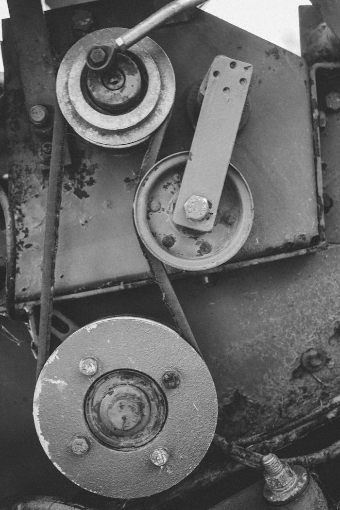 Detailed black and white photo of rusty gears and pulleys in machinery.